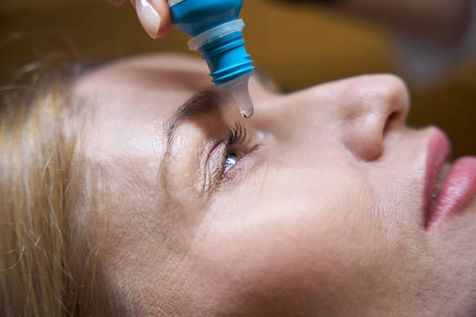 Medical professional demonstrating proper eye irrigation technique for chemical exposure from eyelash tint