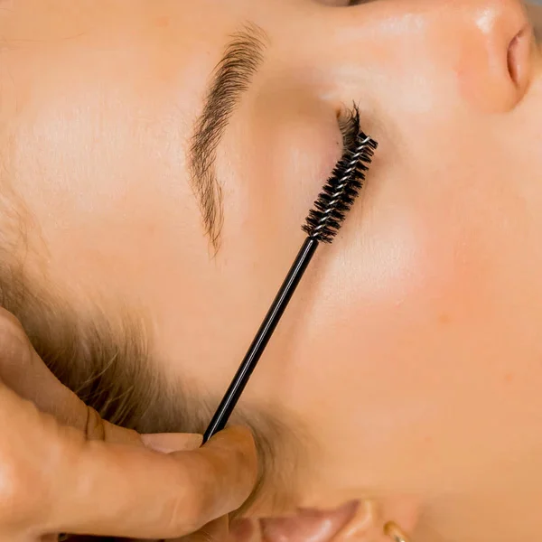 Certified lash technician applying reversal solution to client's over-processed lash lift