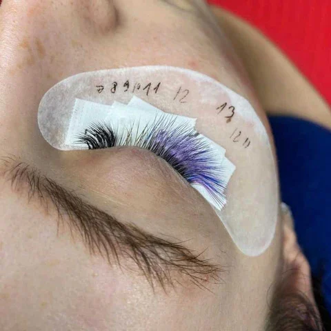 Licensed aesthetician performing mandatory 48-hour patch test behind client's ear before eyelash tinting service